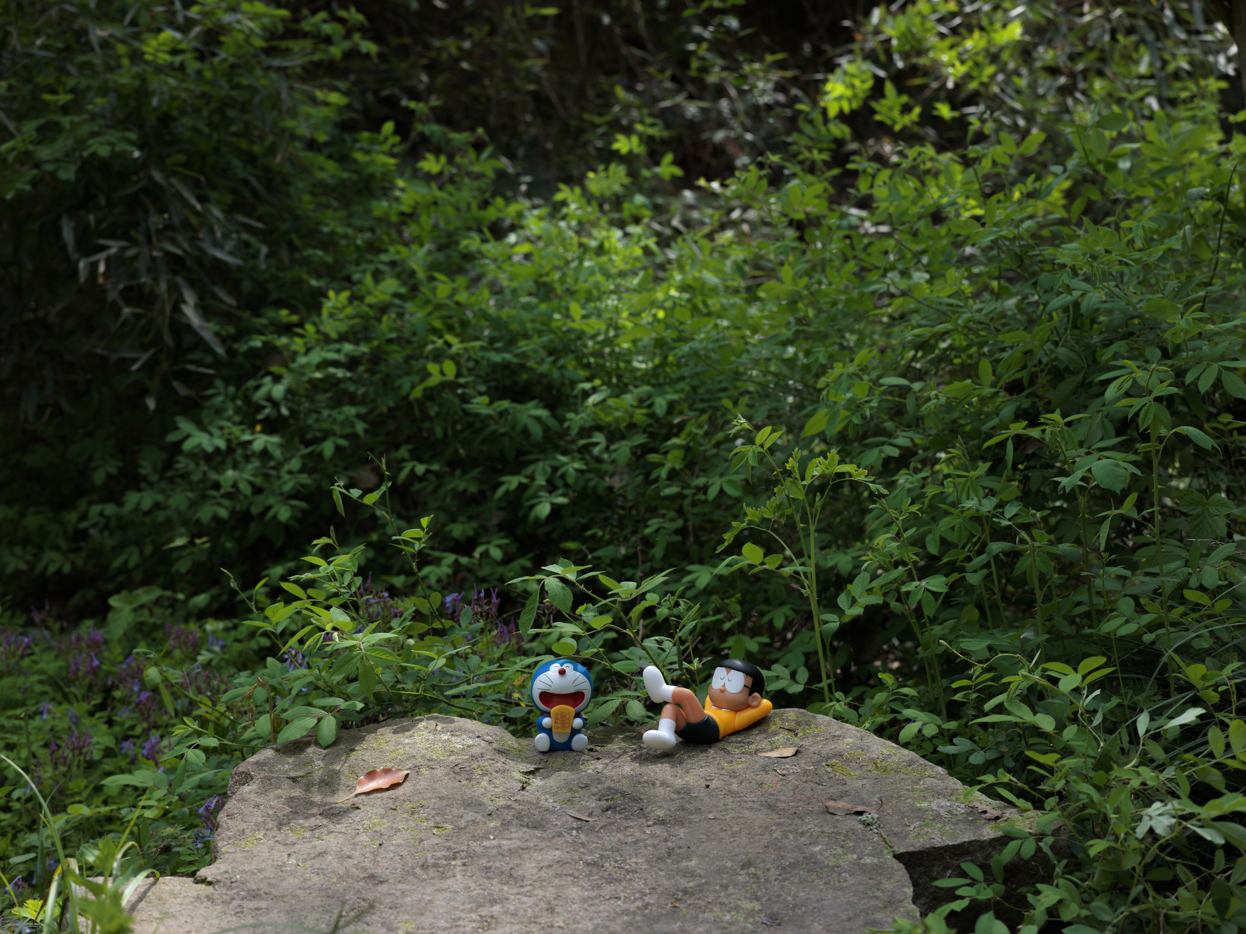 Nobita and Doraemon sitting on a rock